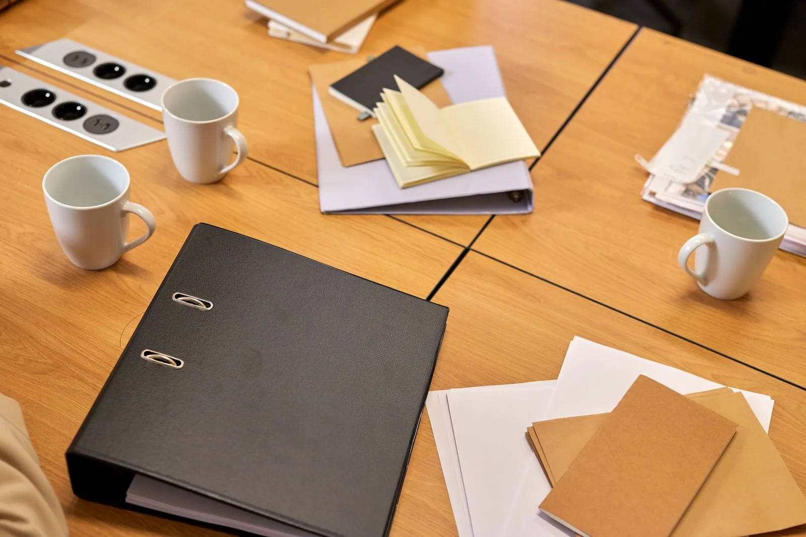 Binders, folders, and note paper arranged on a table for document organization.